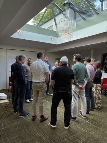 A leadership team standing in a circle during an in-the-room session